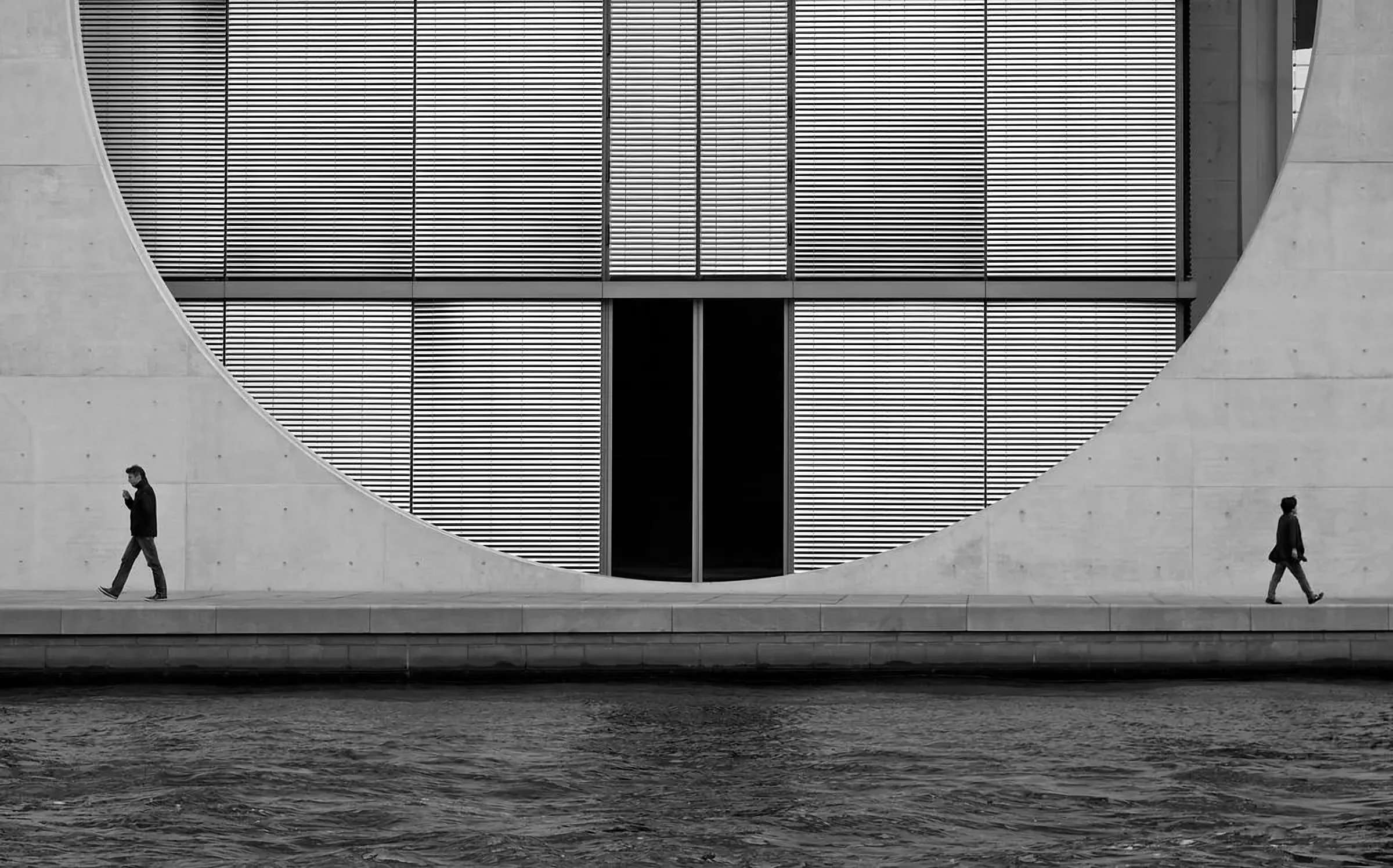 Fachada de hormigón con una gran abertura circular, en blanco y negro
