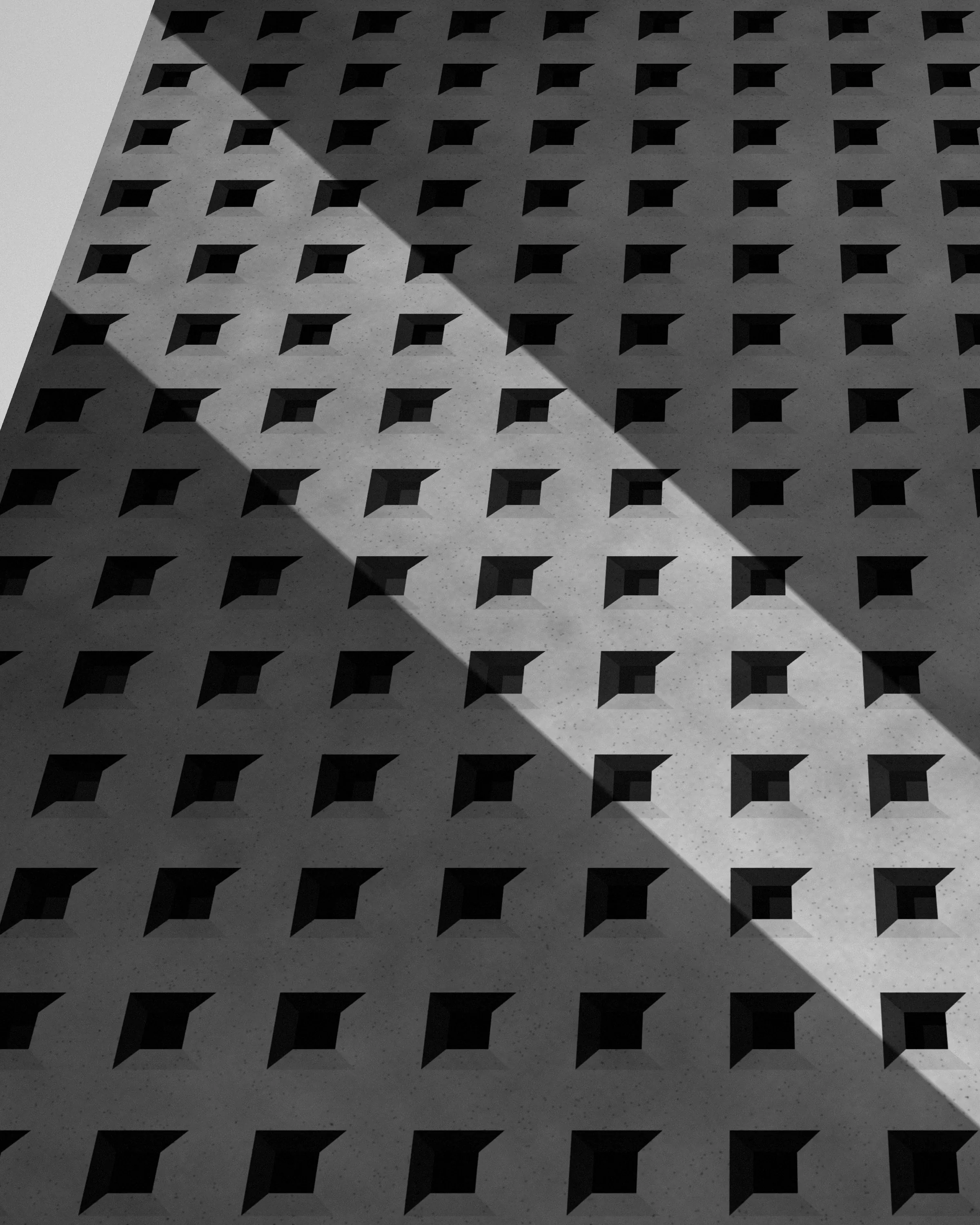 Torre de oficinas en contrapicado con una diagonal de luz, en blanco y negro